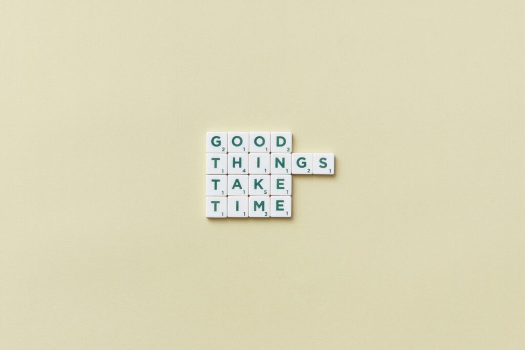 Minimalist image with Scrabble tiles spelling 'Good Things Take Time' on a neutral backdrop.