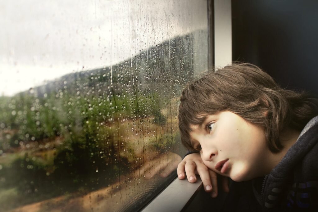 Little boy on a train looking sad, lost and confused. Not knowing where he is going.